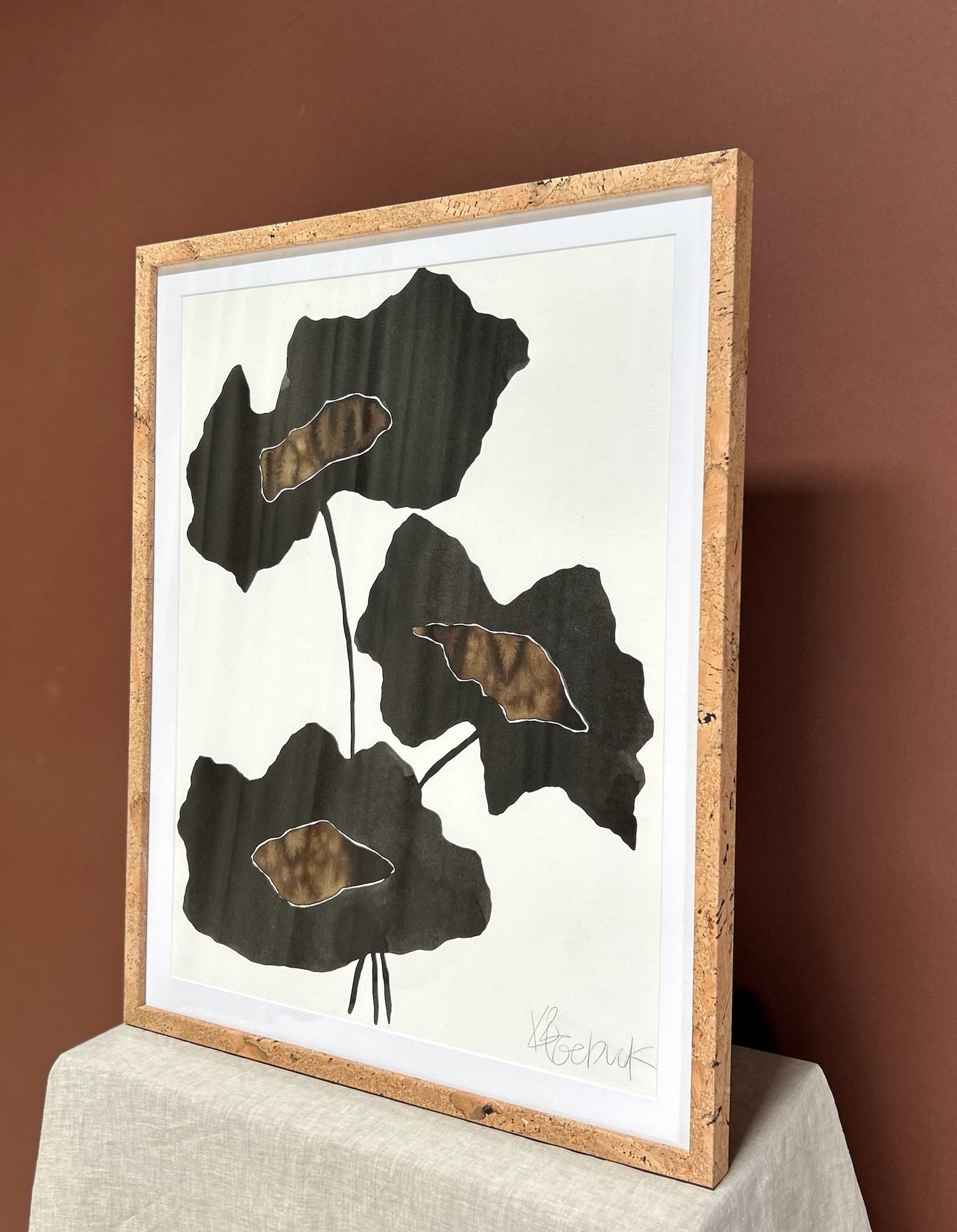 Framed artwork with leaf design on a brown background