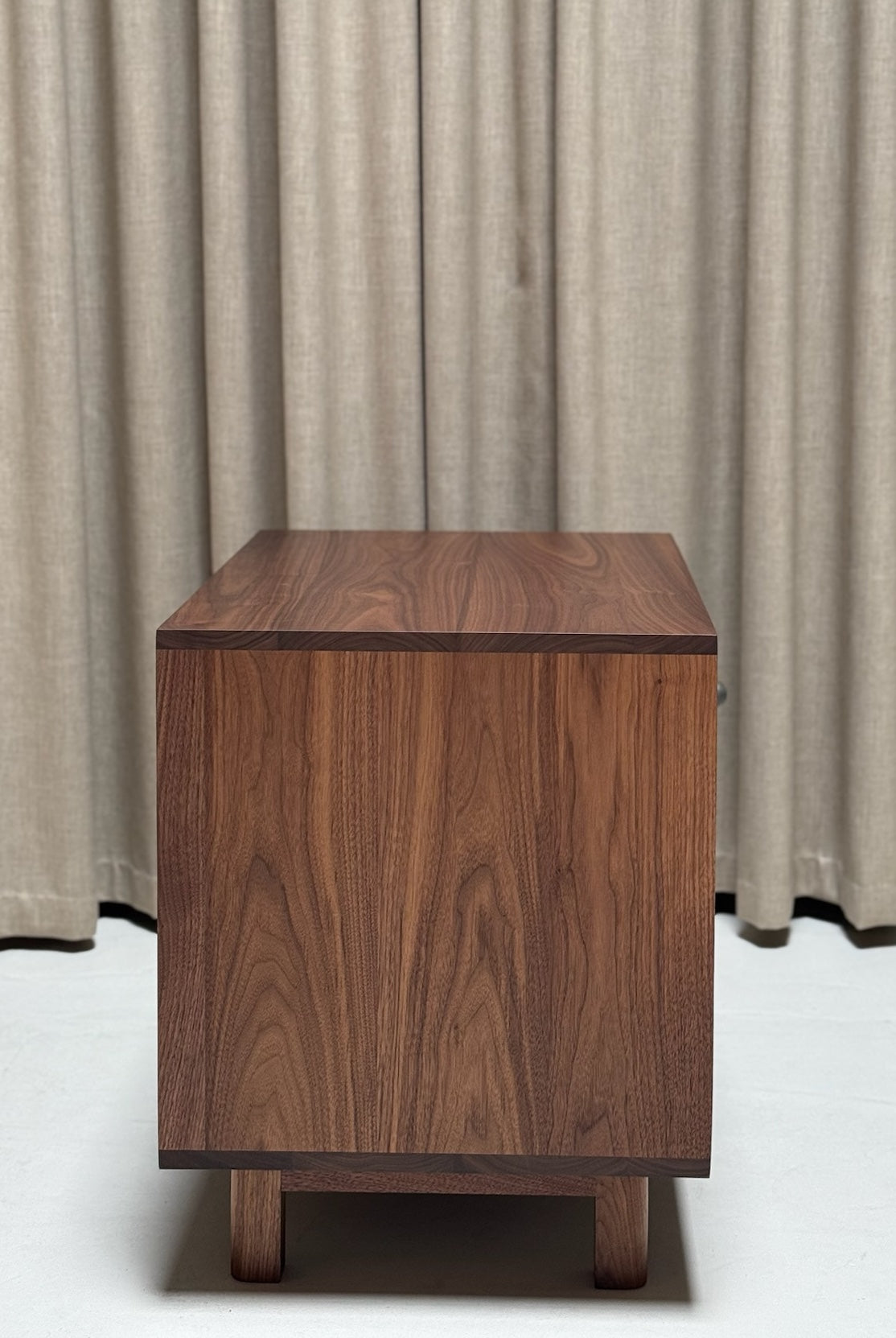 Wooden side table against a beige curtain background
