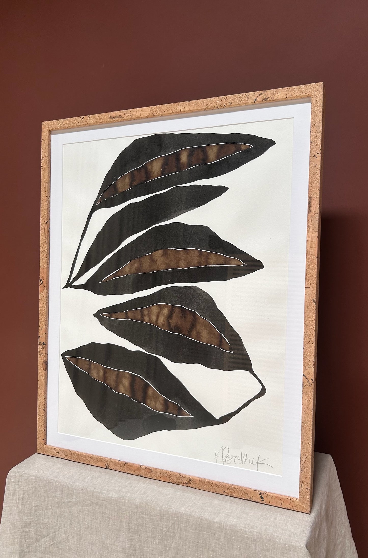 Framed artwork with black leaf design on a white background