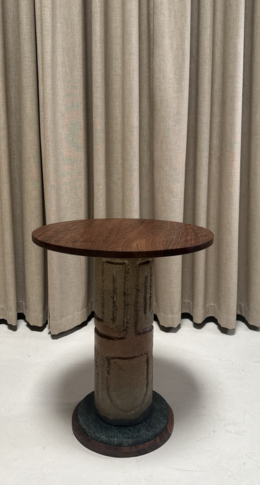 Wooden table on a cylindrical base against a beige curtain background