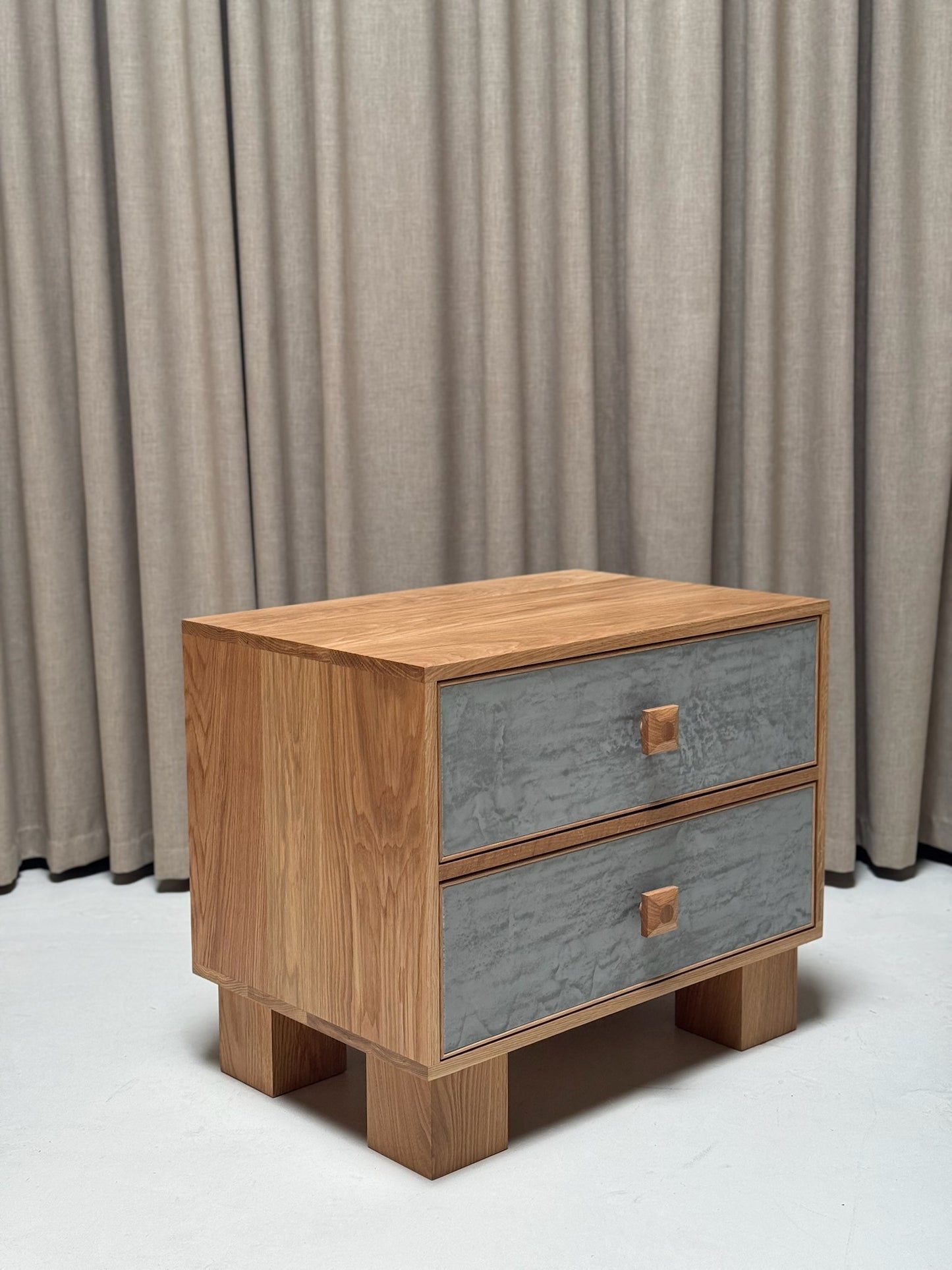 Wooden nightstand with two drawers against a neutral curtain background