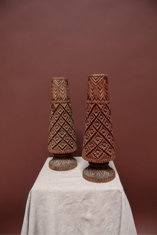 Two wooden carvings on a white cloth against a brown background