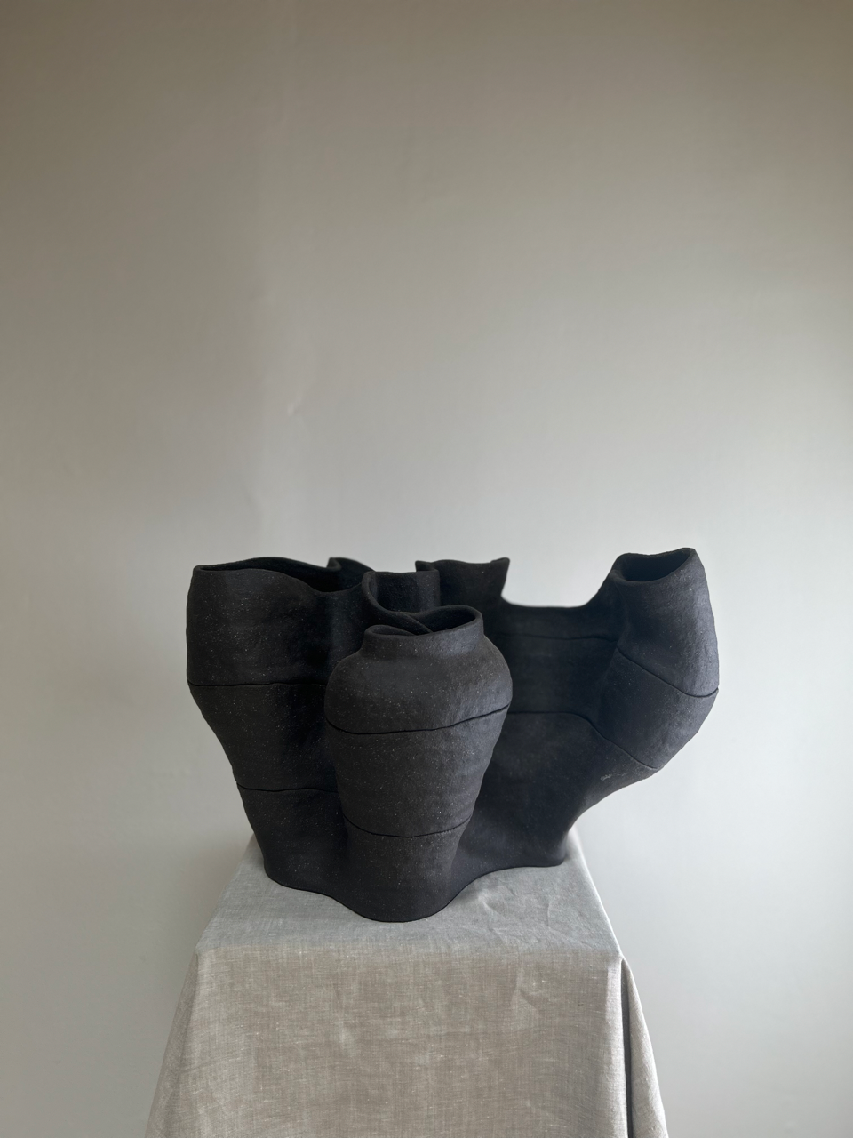 Black ceramic vase with ruffled edges on a light gray surface against a plain background