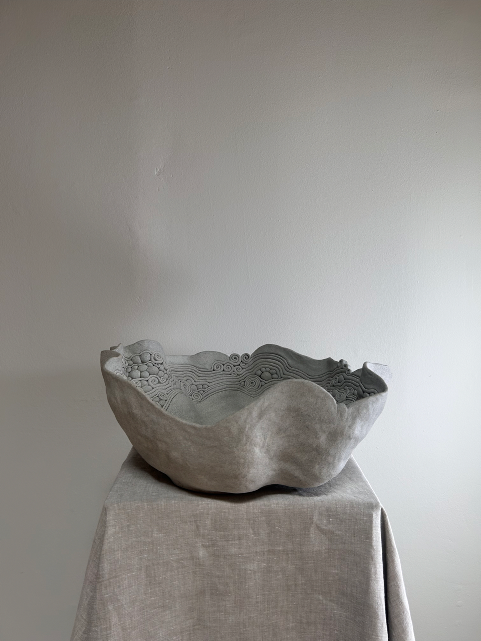 Decorative stone bowl on a draped fabric surface with a plain background