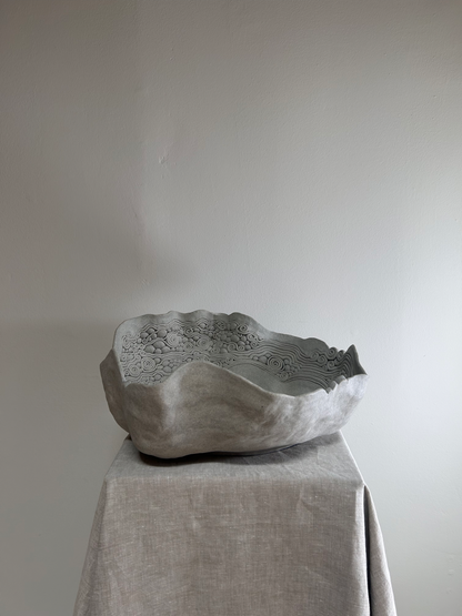 Textured stone bowl on a draped surface with a plain background