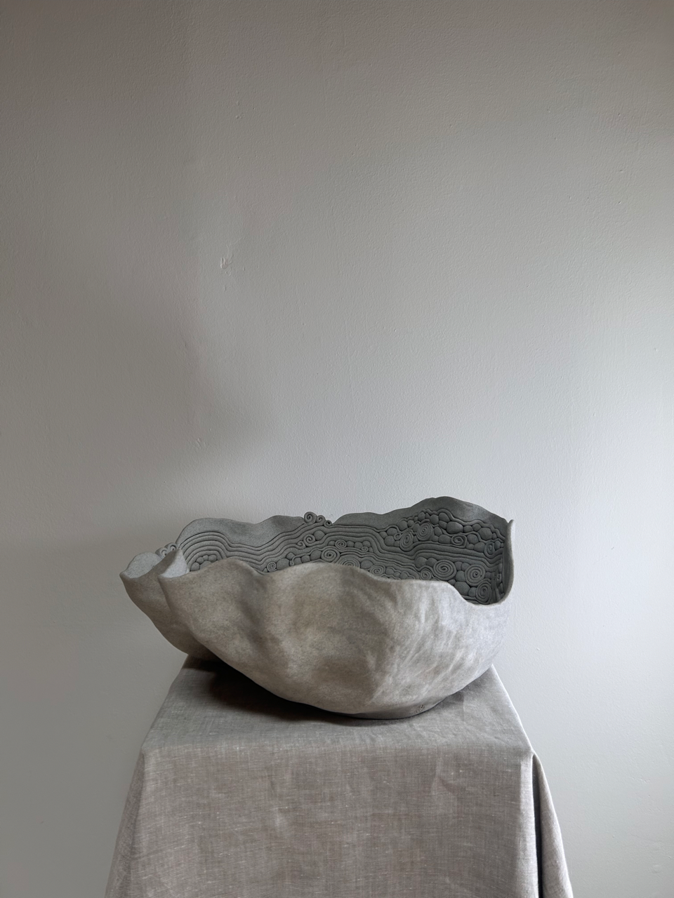 Textured stone bowl on a gray surface with a plain background