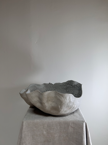 Textured stone bowl on a gray surface with a plain background