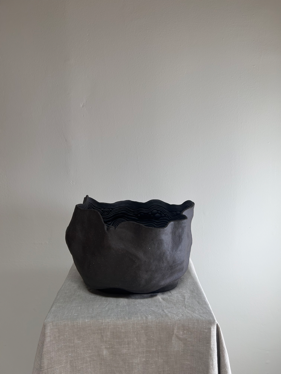 Black woven basket on a light gray surface with a plain white background