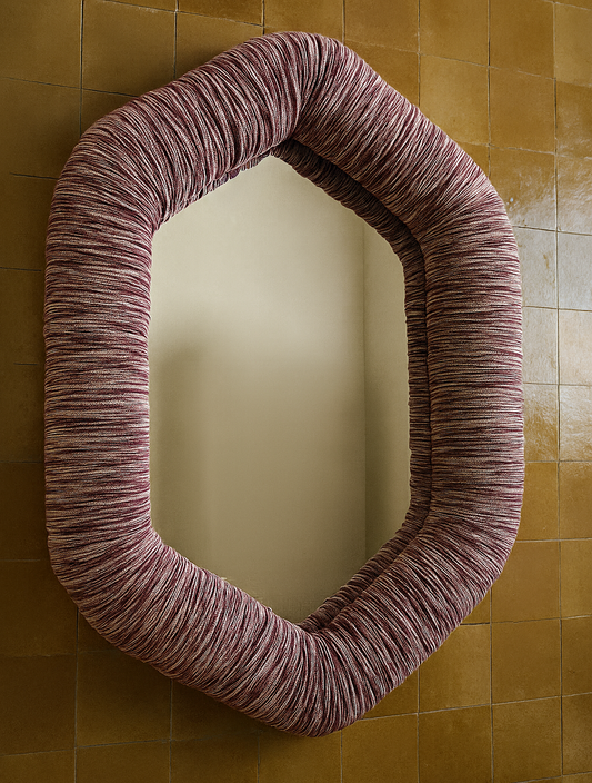 Oval mirror with a upholstered frame Kufri fabric on a tiled wall.