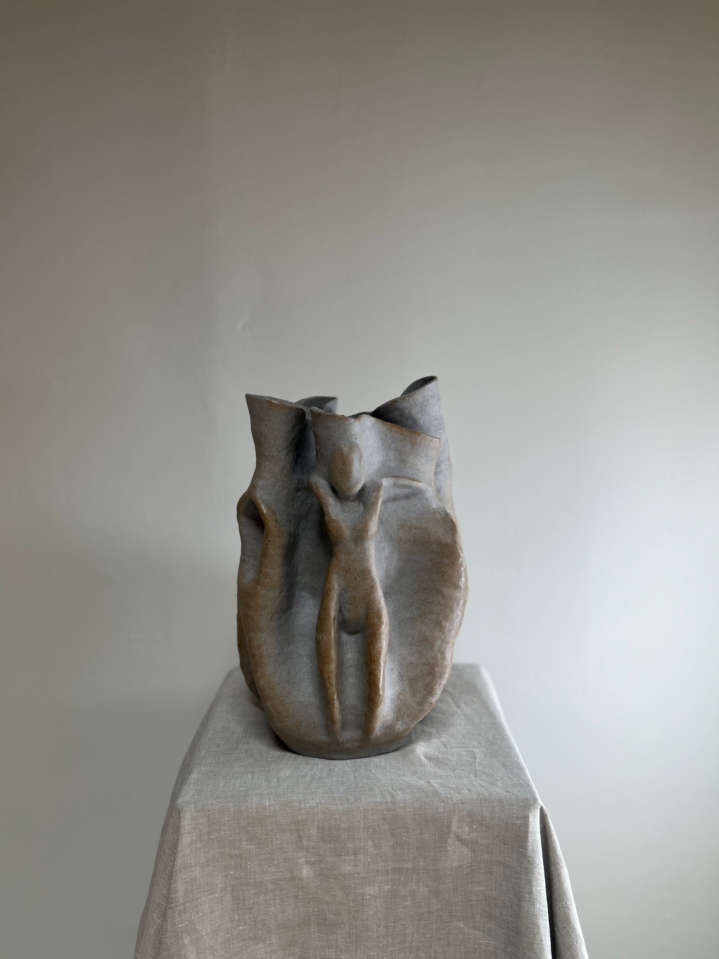 Ceramic vase on a pedestal against a plain background