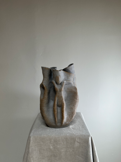 Ceramic vase on a pedestal against a plain background