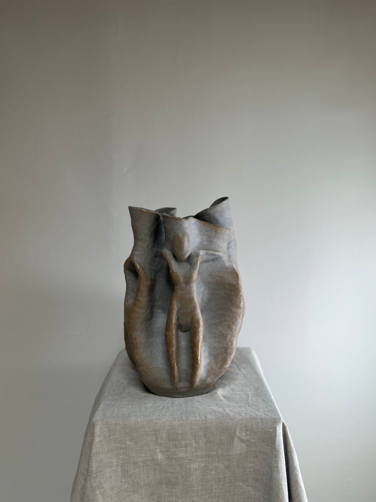 Ceramic vase on a pedestal against a plain background