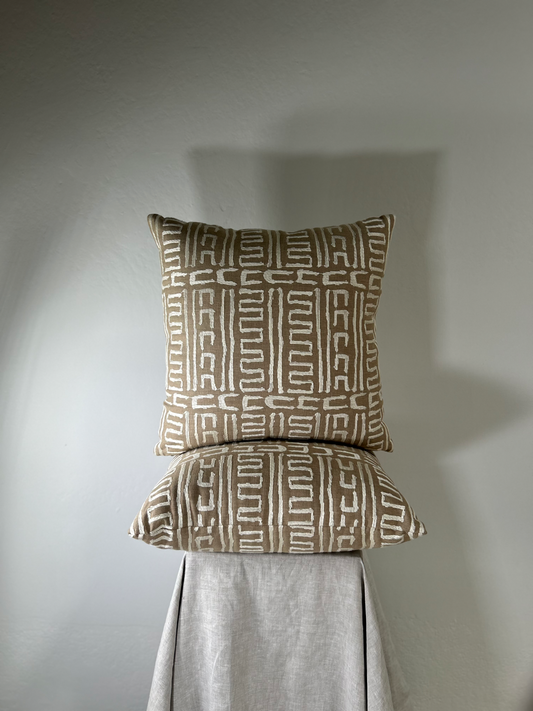 Two patterned pillows on a gray surface with a neutral background