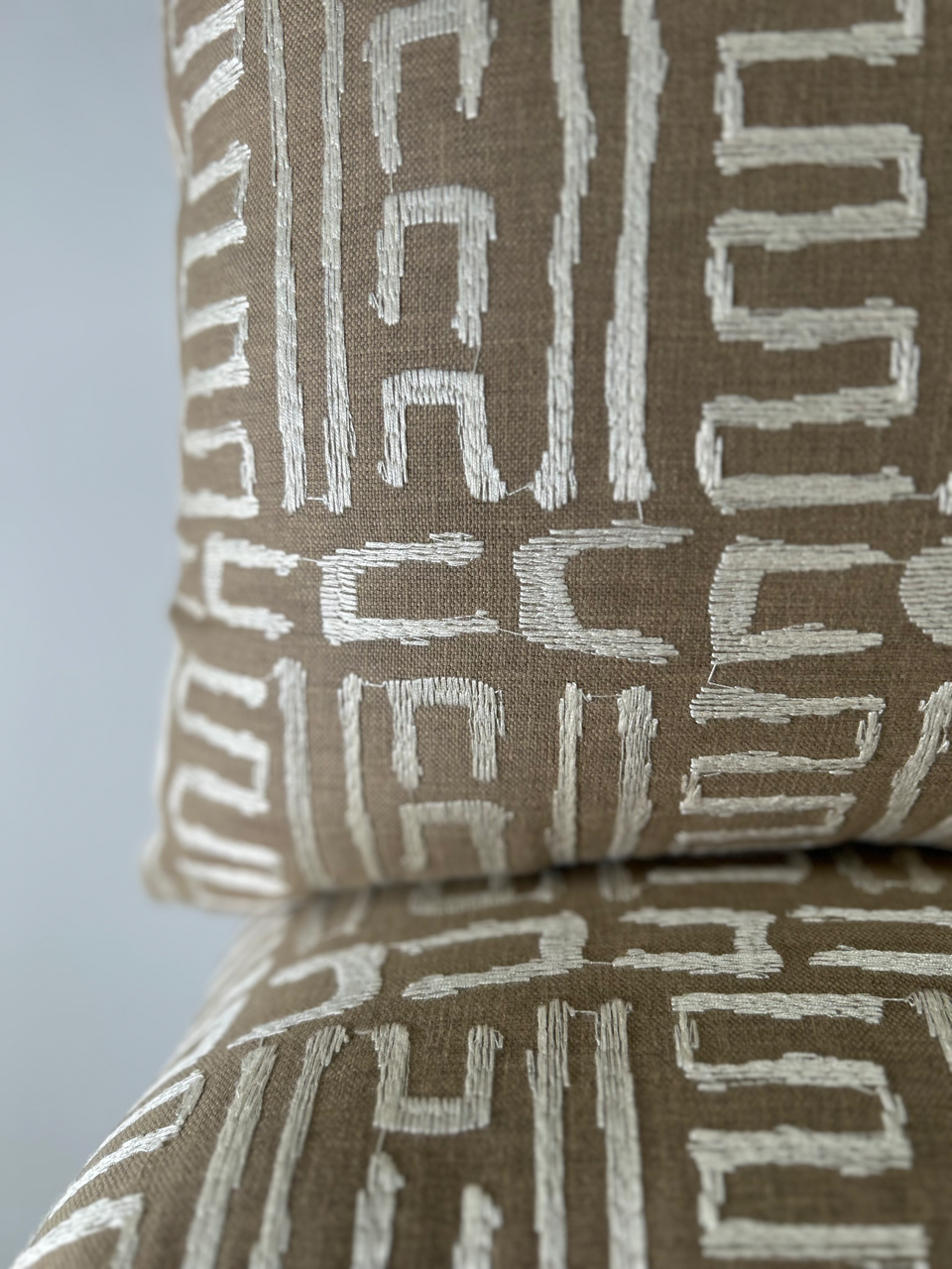 Close-up of a brown pillow with white geometric pattern on a matching surface.