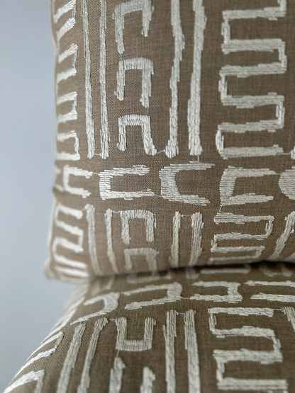 Close-up of a brown pillow with white geometric pattern on a matching surface.