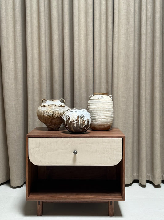Wooden side table with ceramic vases against a beige curtain background