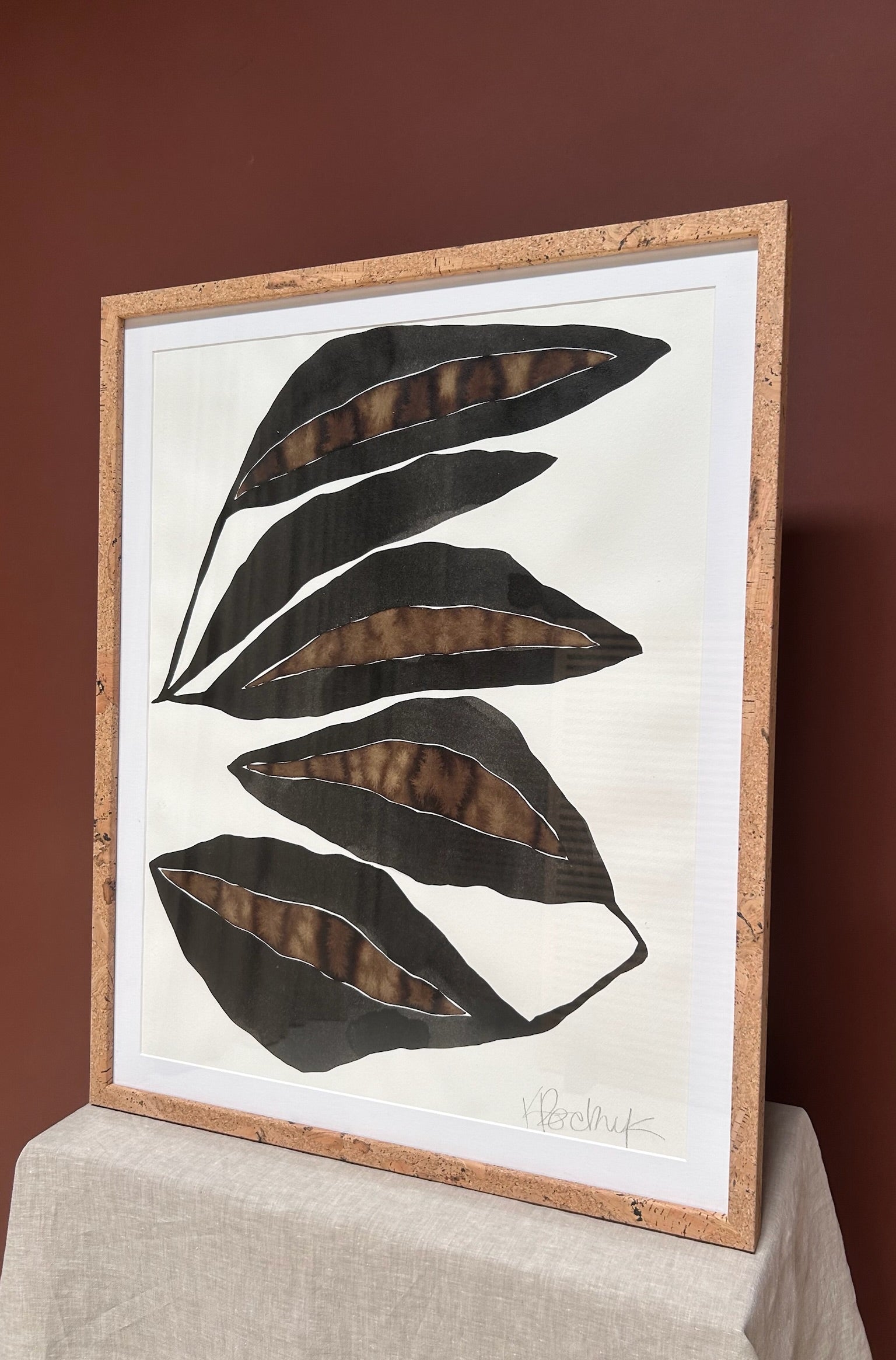 Framed artwork with black leaf design on a white background