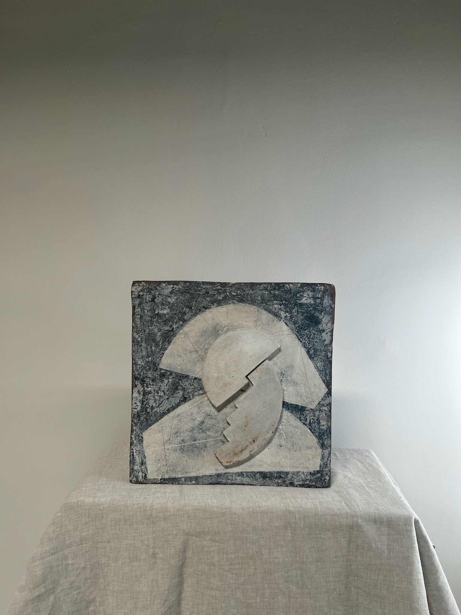 Abstract sculpture on a pedestal against a plain background