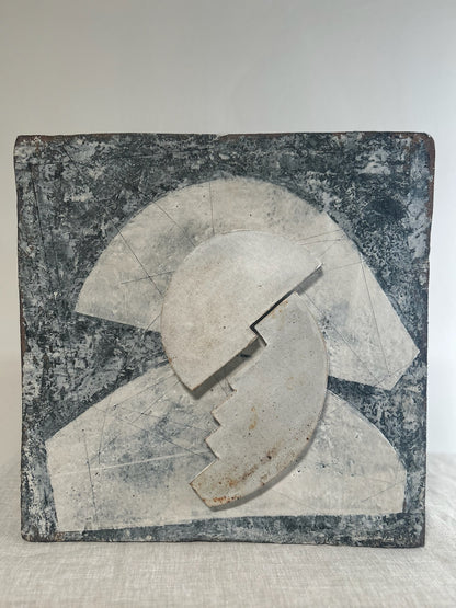 Abstract stone sculpture with geometric design on a textured surface