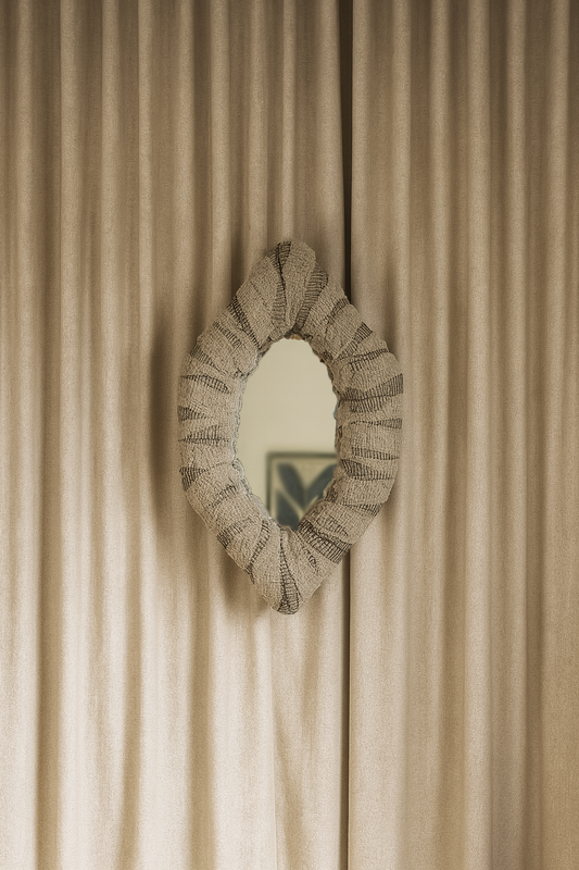 Decorative mirror with textured frame on a beige wall