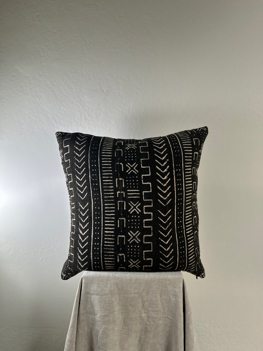 Black patterned pillow on a gray surface with a neutral background